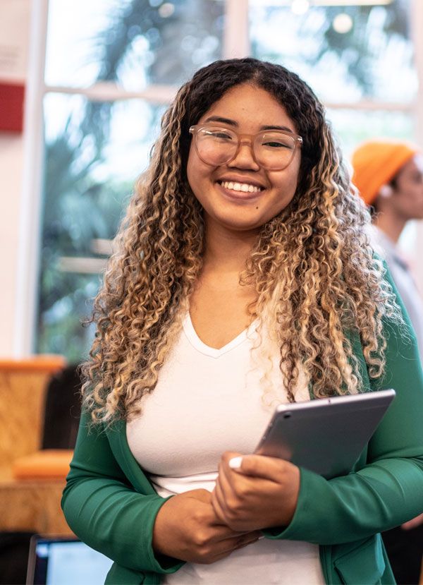A young woman holds a tablet, smiling, at a Teen Creative Lab session in St. Louis.